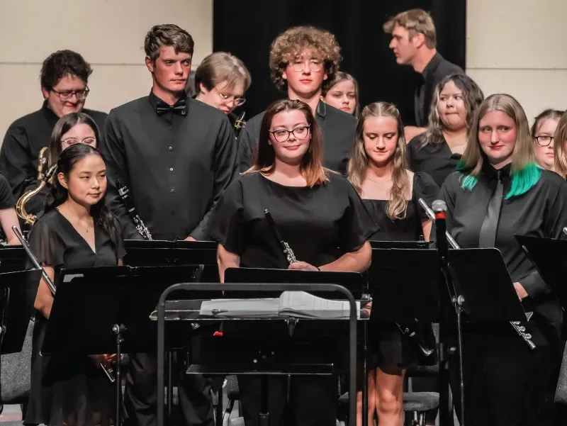 Members of the Symphonic Band stand together at a concert.